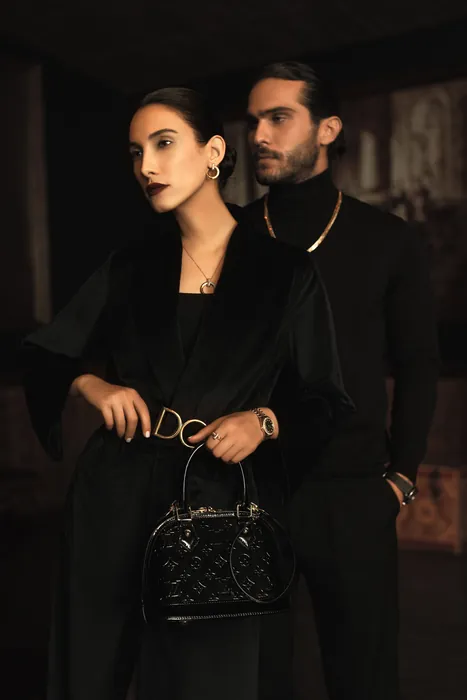 Two guests dressed in black, one holding a structured bag, both wearing watches