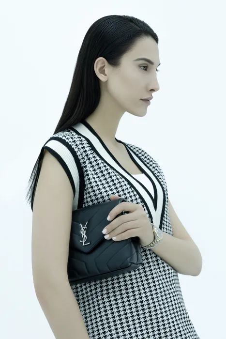 A guest in a houndstooth dress, a small bag and a watch on her wrist