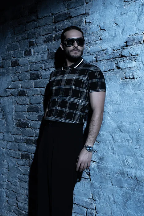 A guest against a lit brick wall, wearing a watch