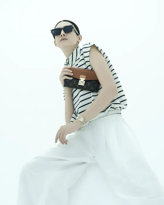 A guest dressed in white, a leather bag and a watch on her wrist